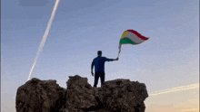 a man stands on top of a rocky hill holding a flag