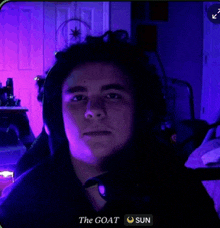 a man wearing headphones and a hoodie with the goat sun written on the bottom