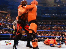 two wrestlers are fighting in a wrestling ring with a w logo on the wall