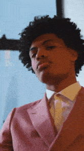a man with curly hair is wearing a pink suit and a white shirt