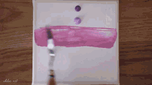 a brush is being used to paint a purple stripe on a white canvas