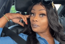 a woman is sitting in the driver 's seat of a car with her hand on her face .