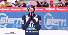 a skier wearing a number 40 jersey stands in front of an advertisement for skechers