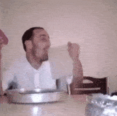 a man is sitting at a table with a bowl of food and a pitcher .