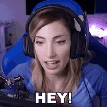 a woman wearing headphones and a blue shirt is sitting in front of a microphone .