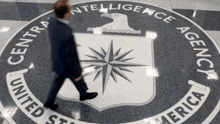 a man walking in front of the intelligence agency logo