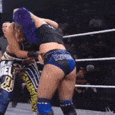 a woman with purple hair is wrestling another woman in a wrestling ring