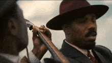 a man in a hat is playing a guitar next to another man in a suit