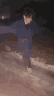 a person in a blue sweater is dancing in the snow .