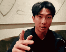 a man is sitting on a couch making a funny face and pointing his finger at the camera .