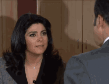a man and a woman are looking at each other and the woman is wearing a necklace