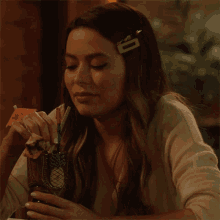 a woman is sitting at a table holding a drink in a pineapple shaped cup .
