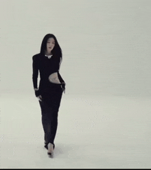 a woman in a black dress is standing in front of a white wall with her eyes closed