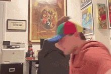 a man wearing a colorful hat is sitting at a desk in front of a hp printer