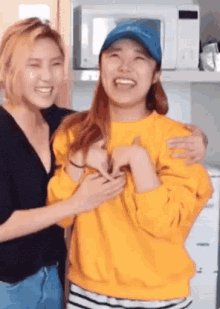 a woman in a yellow sweater is being hugged by another woman in a blue hat .