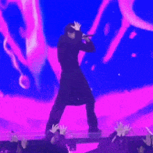 a man is singing into a microphone on a stage in front of a crowd of people .