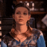 a woman wearing a tie dye top and a necklace