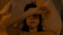 a woman is laying in bed with her hand on her face