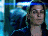 a woman with her eyes closed has a blue light shining on her face