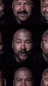 a close up of a man 's face with a beard and a bald head .