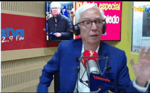 a man wearing headphones stands in front of a microphone in front of a sign that says 2.9 fm on it