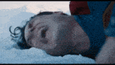 a man in a superman costume is laying in the snow with his mouth open