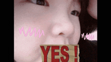 a close up of a person 's face with a yes sign in front of her mouth