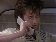 a young man is talking on a cell phone in a car .