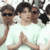 a man in a white shirt is standing in a crowd of people with his hands folded .