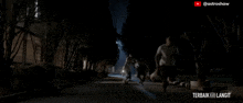 a man is walking down a dark street with the words terbaik ke langit written on the bottom