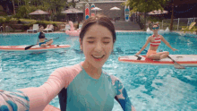 a woman taking a selfie in a swimming pool with other people