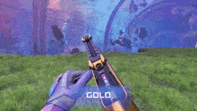a person holding a gun with the word gold on the bottom right