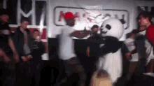 a man in a panda costume is dancing in front of a crowd