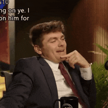 a man in a suit and tie is sitting in front of a sign that says ' $ 10 ' on it