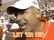 a man wearing a white hat and an orange shirt is screaming and saying let 'er rip .