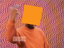 a man wearing an orange shirt has an orange square on his face and the words yeah yeah yeah yeah