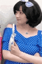 a woman wearing a blue polka dot dress with a bow on her hair