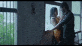 a man and a woman are kissing in front of a window in the rain .