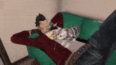 a man is laying on a green couch with a cat on his chest