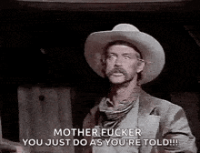 a man in a cowboy hat is talking to another man in a black and white photo .