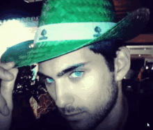 a man with blue eyes is wearing a green hat with spades on it