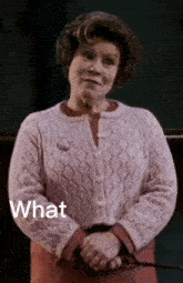 a woman in a pink sweater is holding a wand and the word what is on the bottom