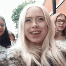 a woman with blonde hair and glasses is smiling in front of two other women