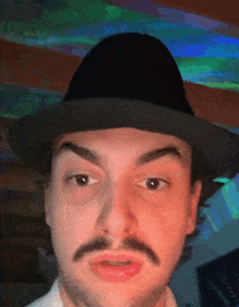 a man with a mustache is wearing a hat .