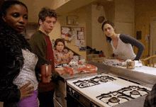 a group of people standing around a stove in a kitchen with a sign on the wall that says ' i love you '