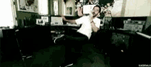 a man in a white shirt is singing into a microphone in a recording studio .