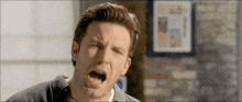 a man is making a funny face with his mouth open in a room .