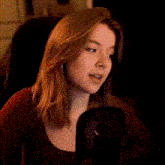 a woman with long red hair is sitting in front of a microphone and talking into it .