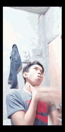 a young man in a gray shirt is standing in a room