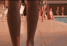 a woman 's legs are shown as she walks by a pool